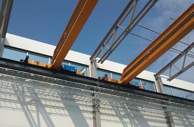 Single girder overhead travelling crane in half open production hall of LECOR Stålteknik company for building steel things