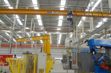 Crane operator uses overhead travelling crane to transport load to build components for grain harvesters